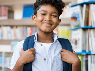 Young boy in a library wearing a backpack